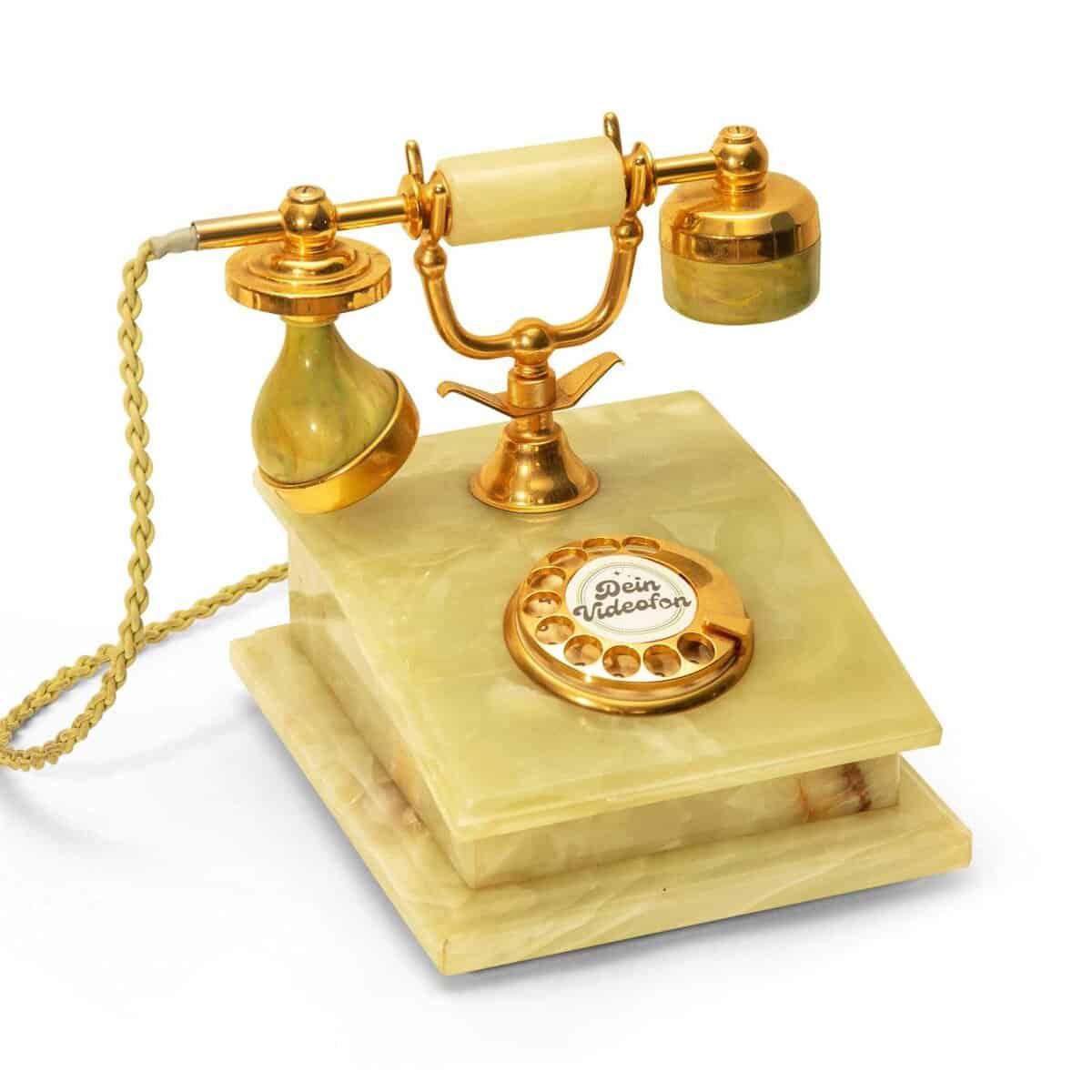 Ein Vintage-Drehtelefon mit goldenen und marmorähnlichen Elementen, mit einem Hörer, einer Wählscheibe und dekorativen Details.