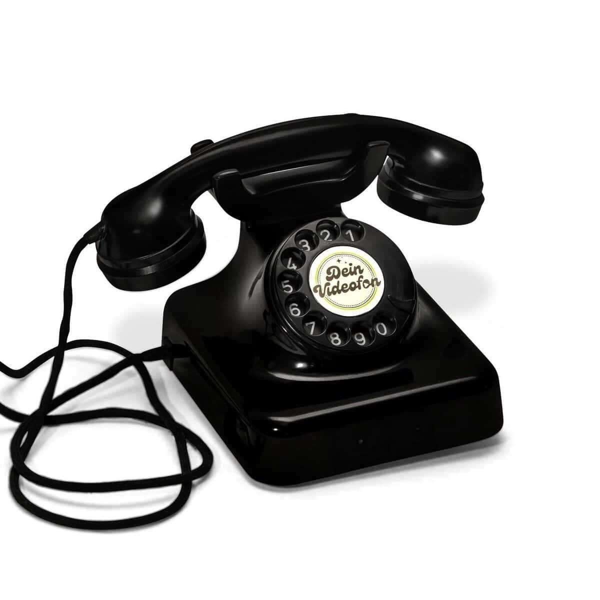 Ein schwarzes Wählscheibentelefon mit einer aufgewickelten Schnur und der Aufschrift Dein Videoton in der Mitte der Wählscheibe.